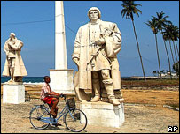 Boy cycles past colonial-era statue, Sao Tome